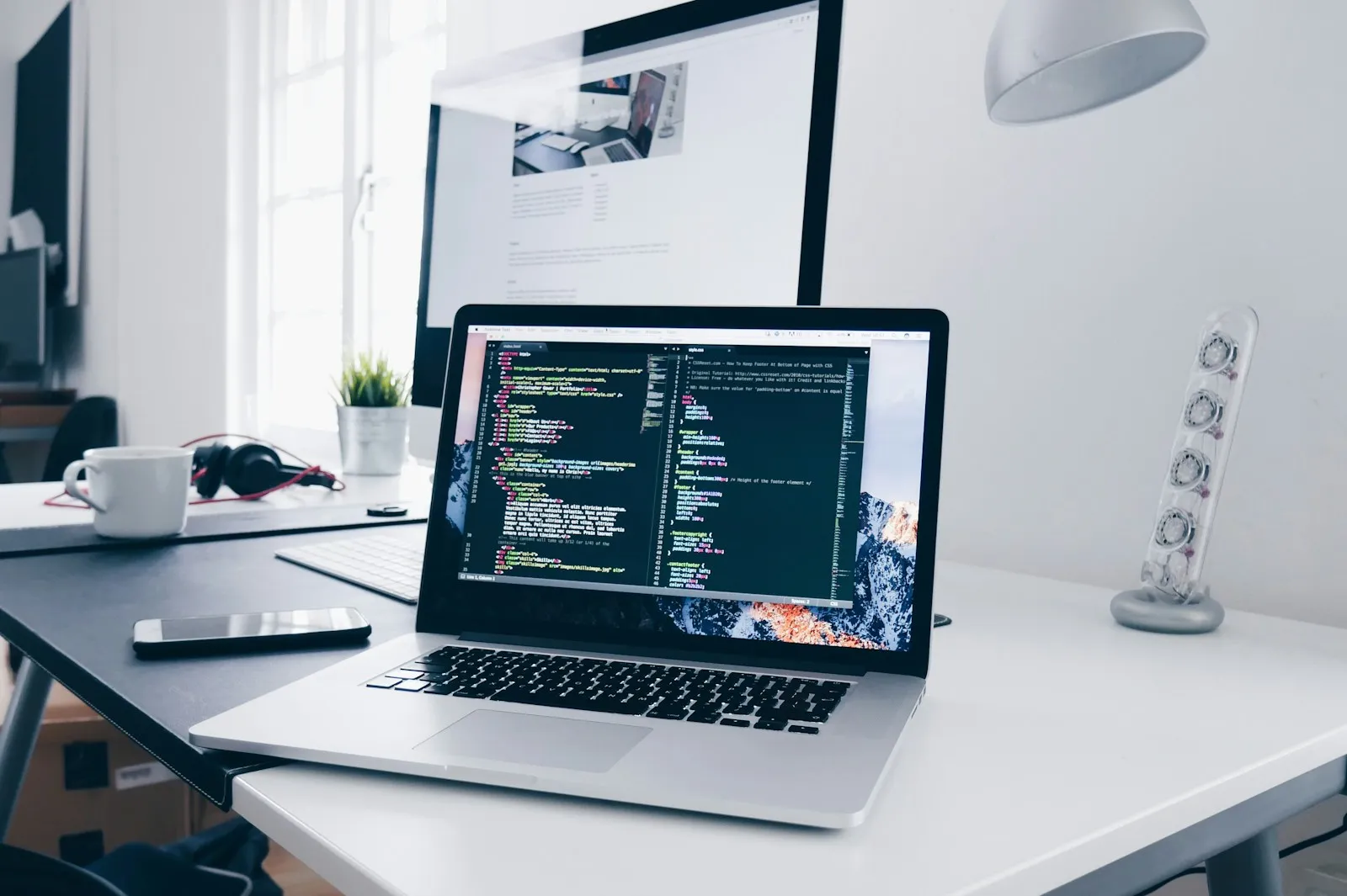 A MacBook on a busy desk displaying lines of structured text and code, representing the kind of structured AI-assisted output that benefits from a human review pass before shipping.