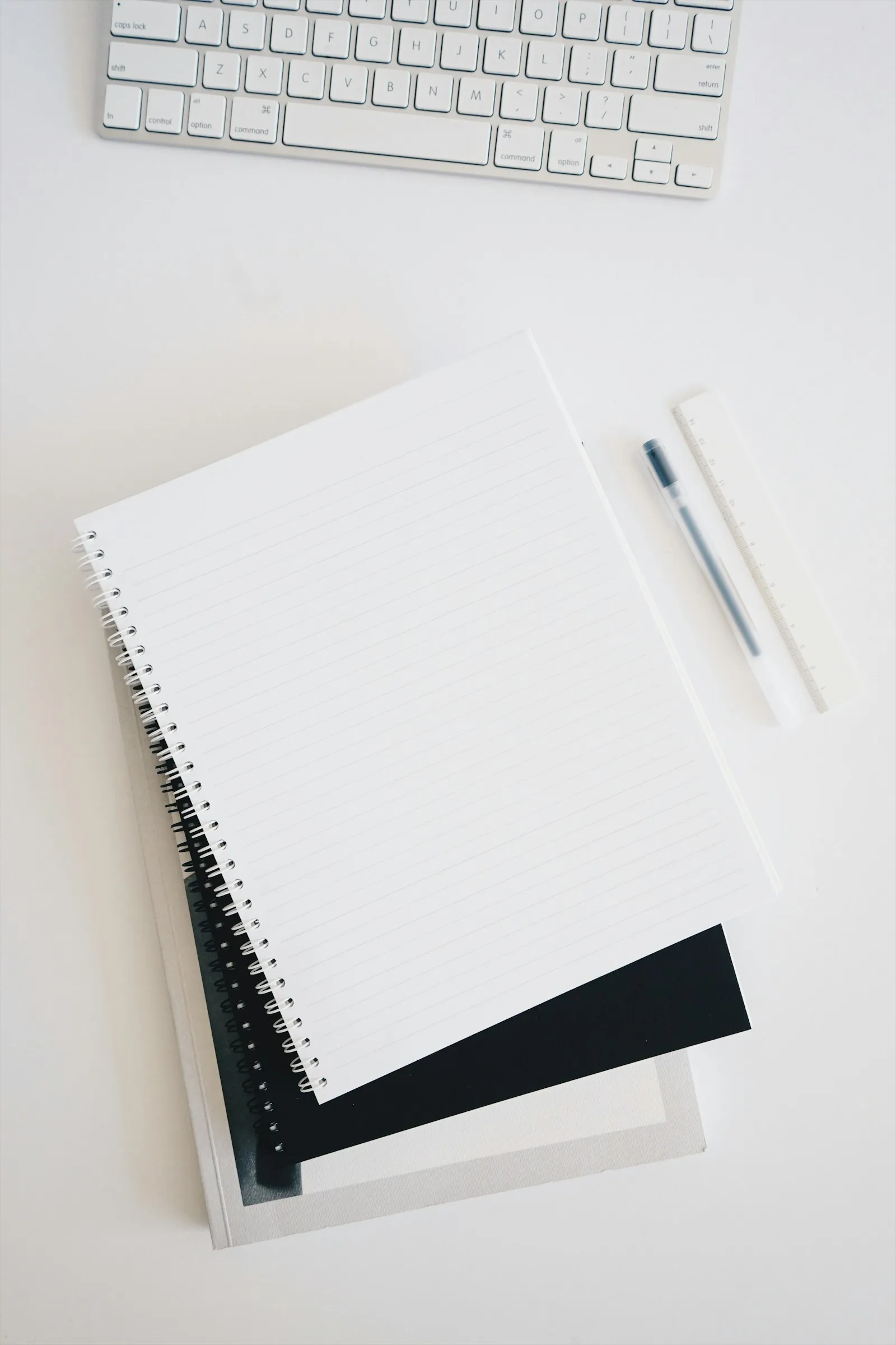 An empty spiral notebook beside a keyboard and pen, the typical workspace of an owner planning the first 90 days of a brand new business.