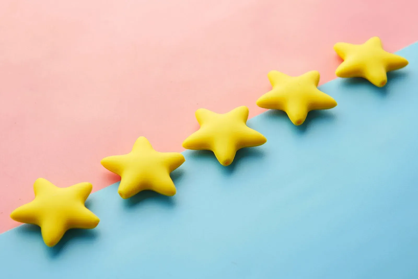 Yellow rating stars arranged on a blue and pink surface, representing customer reviews and star ratings.