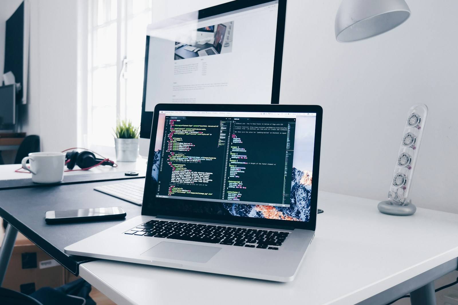A MacBook on a busy desk displaying lines of structured text and code, representing the kind of structured AI-assisted output that benefits from a human review pass before shipping.